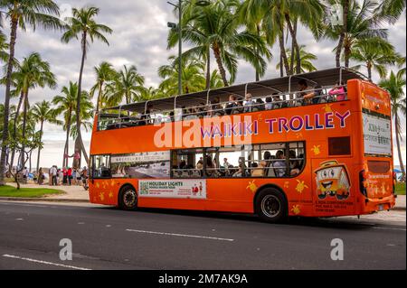 Honolulu, Hawaï - 29 décembre 2022 : le tramway de Waikiki qui prend les touristes sur l'avenue Kalakaua. Banque D'Images