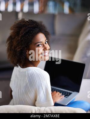 Se détendre avec Internet. Prise de vue sur l'épaule d'une jeune femme utilisant un ordinateur portable à la maison. Banque D'Images