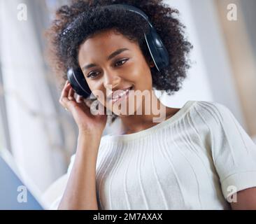 Détendez-vous avec des morceaux géniaux. une jeune femme qui écoute de la musique à l'aide de son casque. Banque D'Images