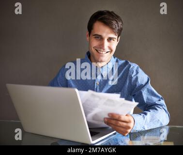 Mes concurrents améliorent Fais attention. Portrait d'un homme d'affaires tenant des documents tout en étant assis devant son ordinateur portable. Banque D'Images