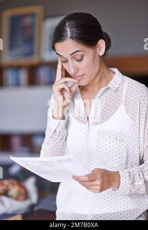 Passer en revue les changements. une belle jeune femme considérant un document entre ses mains. Banque D'Images