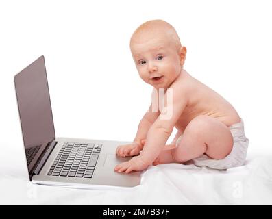 Hes already learning the ways of technology. A baby boy with a laptop. Stock Photo