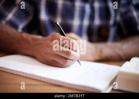 Les bonnes notes sont la clé de bons résultats. Gros plan d'un jeune étudiant qui écrit sur un bloc-notes. Banque D'Images