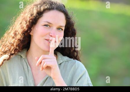 Bonne femme demandant le silence dehors avec le doigt sur les lèvres Banque D'Images