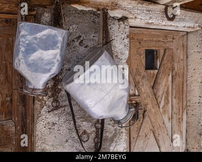 Sacs à dos en aluminium pour le transport du lait après la traite, accrochés devant la grange. Banque D'Images
