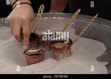 Le café turc est placé dans du sable chaud pour la préparation. Une méthode traditionnelle de préparation du café en Turquie. Banque D'Images