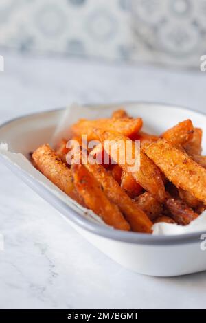 Frites de patate douce dans un bol en émail blanc. Sur fond de marbre Banque D'Images