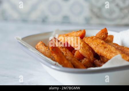 Frites de patate douce dans un bol en émail blanc. Sur fond de marbre Banque D'Images