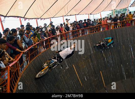 Mumbai, Inde. 08th janvier 2023. Un homme à bord d'une moto à l'intérieur de Maut ka Kuan (puits de la mort) réalise des cascades pendant la foire Erangal à Mumbai. La foire est également connue sous le nom de fête de St.Bonaventure. Il marque le baptême ou la cérémonie de dénomination de Jésus-Christ et est comme une réunion annuelle du peuple de la communauté est indienne. Les gens viennent et offrent la prière à l'église Saint-Bonaventure qui est située sur la plage, poste qu'ils aiment les manèges d'amusement sur la plage et de cuisiner la nourriture et de manger là. Crédit : SOPA Images Limited/Alamy Live News Banque D'Images