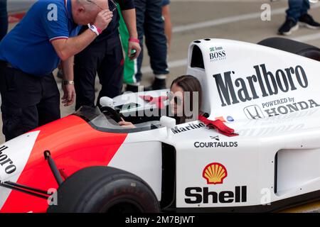 Une jeune dame, assise dans le cockpit d'une McLaren 1992 MP4/7, après la démonstration de la piste, organisée par Ignition GP 90s F1, au Silverstone Classic 2022 Banque D'Images