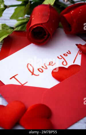 Mettez en place des boîtes en forme de coeur décorées de coeurs roses et rouges sur fond rouge Banque D'Images