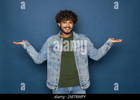 Jeune homme barbu portant un T-shirt noir sur fond bleu studio confondent et s'interroge sur la question. Incertain avec le doute, pensant avec la main sur hea Banque D'Images