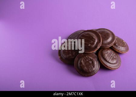 photo d'un grand nombre de biscuits enrobés de chocolat sur fond violet Banque D'Images