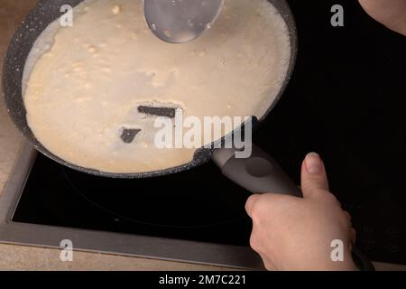 pâte à crêpes photo sur une casserole chaude, mains dans le cadre Banque D'Images
