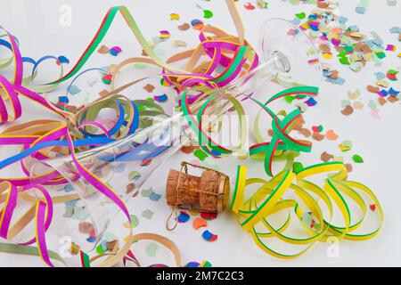 Liège de champagne avec muselet, banderoles en papier, confetti et coupe de champagne vide au sylvester Banque D'Images