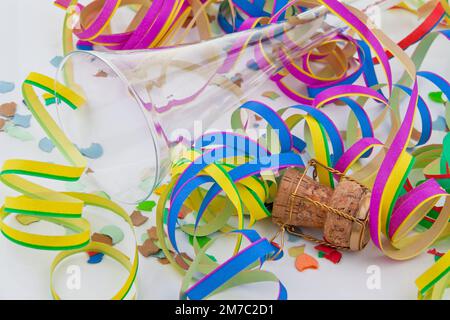 Liège de champagne avec muselet, banderoles en papier, confetti et coupe de champagne vide au sylvester Banque D'Images