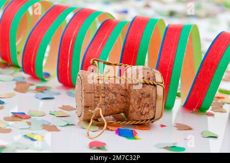 Liège de champagne avec muselet, banderole en papier et confetti au sylvester Banque D'Images