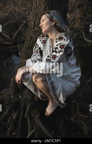 Gros plan femme souriante dans une chemise ukrainienne en train de profiter d'un portrait de forêt silencieux Banque D'Images