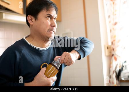 L'homme tire un biberon coincé dans une tasse ou une tasse. Banque D'Images