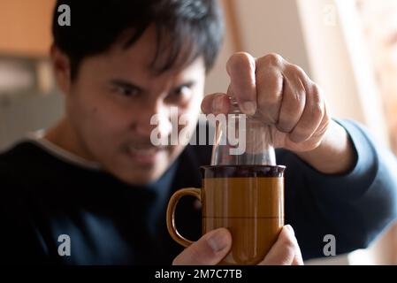 L'homme tire un biberon coincé dans une tasse ou une tasse. Banque D'Images