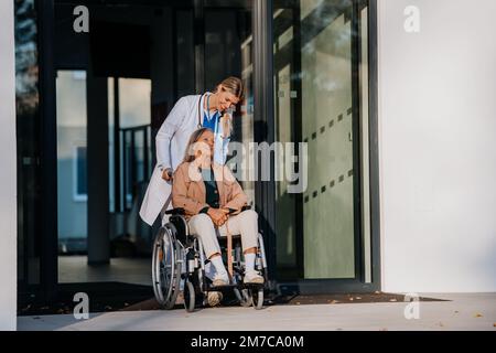 Jeune femme médecin prenant soin d'une femme âgée en fauteuil roulant. Banque D'Images