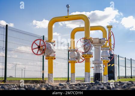 Vannes de gaz dans le centre de distribution - tuyaux en acier épais jaune contre le ciel avec des nuages Banque D'Images