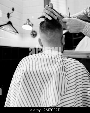 barber coupe les ciseaux du client dans le salon. un homme est assis dans un barbershop Banque D'Images