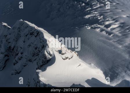 Vue aérienne sur les champs de glace des Alpes du Sud en Nouvelle-Zélande, avec une crête montagneuse, des motifs intéressants et des crevasses glaciaires. Banque D'Images