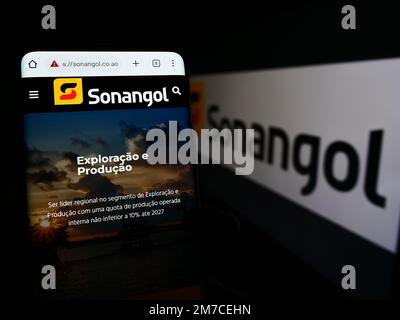 Personne tenant un smartphone avec la page Web de la société pétrolière angolaise Group Sonangol sur l'écran devant le logo. Concentrez-vous sur le centre de l'écran du téléphone. Banque D'Images