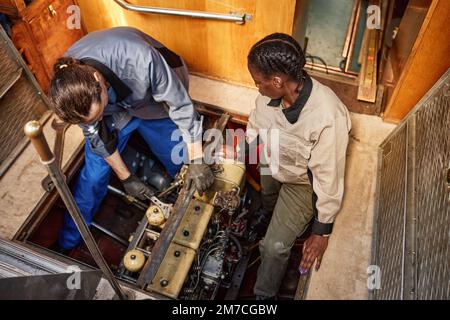 Vue de dessus de deux personnes réparant le moteur de bateau dans la fosse, copier l'espace Banque D'Images