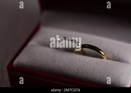 deux anneaux de mariage l'un est jaune or et l'autre est blanc or dans une boîte rouge doux Banque D'Images