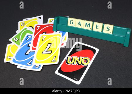Un concept de nuit de jeux montrant des tuiles scrabble en épelant les jeux de mots sur une portée et des cartes UNO s'étaler sur un fond noir isolé Banque D'Images