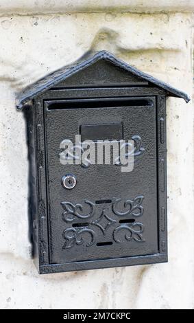 Boîte aux lettres noire placée sur le mur. Banque D'Images