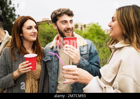 Groupe de jeunes amis parlant ensemble à l'extérieur et tenant des verres de bière en plastique rouge insouciant - concept de vie de personnes Banque D'Images