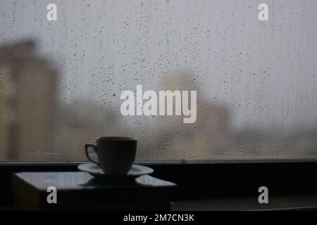 Vue par une fenêtre avec des gouttes de pluie sur elle à d'autres maisons sur un jour pluvieux, thé, et bougies, Antalya, Turquie. Banque D'Images
