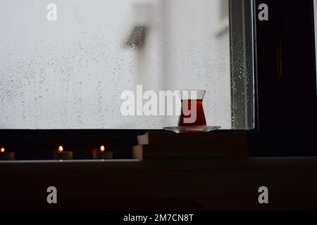 Vue par une fenêtre avec des gouttes de pluie sur elle à d'autres maisons sur un jour pluvieux, thé, et bougies, Antalya, Turquie. Banque D'Images