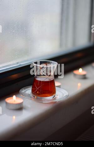 Vue par une fenêtre avec des gouttes de pluie sur elle à d'autres maisons sur un jour pluvieux, thé, et bougies, Antalya, Turquie. Banque D'Images
