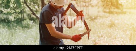faucher l'herbe traditionnelle à l'ancienne avec des scythe à la main sur la ferme du village. un jeune agriculteur aiguise des scythe avec de l'herbe ou de la pierre à affûter pour Banque D'Images