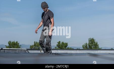 Les ingénieurs de l'équipe masculine installent un système autonome de panneaux photovoltaïques solaires. Les électriciens montant le module solaire bleu sur le toit du toit de l'entreprise. Alternati Banque D'Images