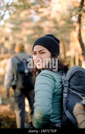 Bonne femme regardant sur l'épaule tout en randonnée dans la forêt Banque D'Images