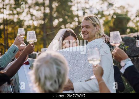 Couple jeune et souriant dansant au milieu de la famille et des amis lors du mariage Banque D'Images