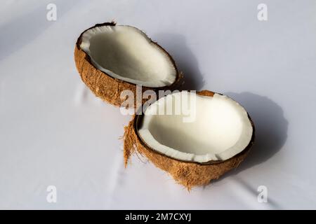 Fruit tropical concept, deux moitiés de noix de coco blanc frais sur fond de tissu blanc. Banque D'Images