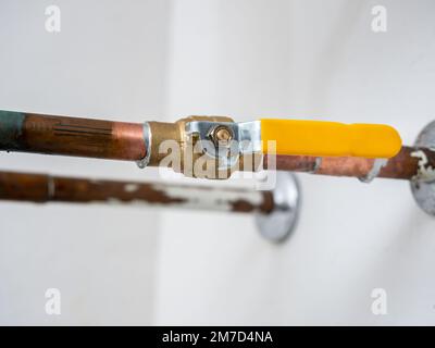 Vanne d'arrêt d'eau. Tuyau de plomberie en cuivre avec vanne d'alimentation en eau en laiton et poignée de robinet jaune. Banque D'Images