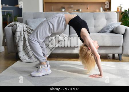 La femme effectue un exercice de pont à la maison Banque D'Images
