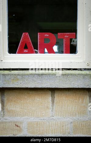 Un petit signe palstique dans la fenêtre d'une classe d'école qui indique le mot ART. Banque D'Images