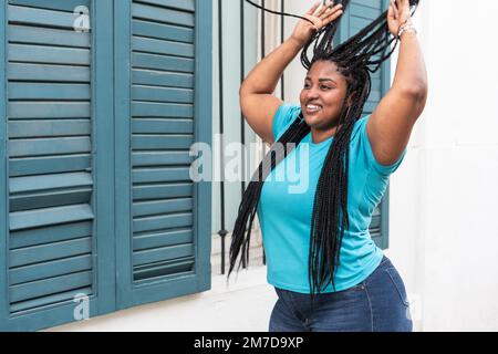 Portrait d'une femme noire dans un chemisier bleu tenant ses tresses. Banque D'Images