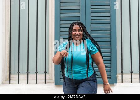 Femme africaine avec de longues tresses dansant dans la ville très heureux Banque D'Images