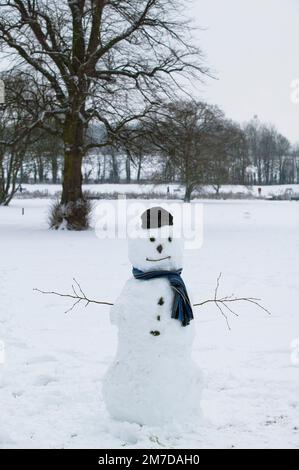 Un bonhomme dans la neige fraîchement tombée d'un seul hiver britannique dans un parc dans la ville de Gloucestershire Cirencester au Royaume-Uni. Banque D'Images