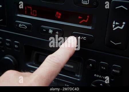 Touche de climatisation dans une voiture appuyée par le doigt conducteur. Banque D'Images