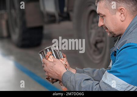 Le mécanicien d'automobiles répare le chariot. Réparation et diagnostic professionnels des tracteurs et équipements cargo. Le mécanicien en atelier considère les pièces de rechange. Banque D'Images